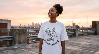 Black woman with natural curly afro wearing Rise Above The Noise black tee with detailed phoenix graphic and gold chains